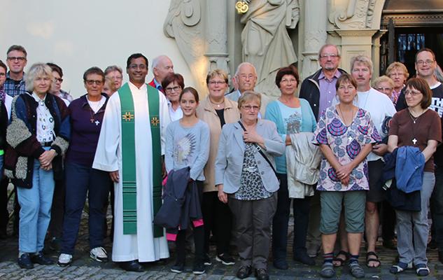 Auf dem Bild steht die Kirchengemeinde zusammen mit dem Pfarrer vor dem Eingang der Kirche