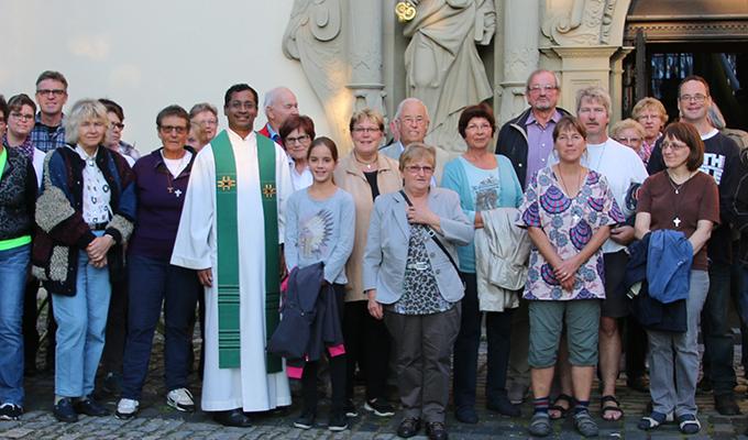 Auf dem Bild steht die Kirchengemeinde zusammen mit dem Pfarrer vor dem Eingang der Kirche