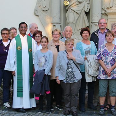 Auf dem Bild steht die Kirchengemeinde zusammen mit dem Pfarrer vor dem Eingang der Kirche