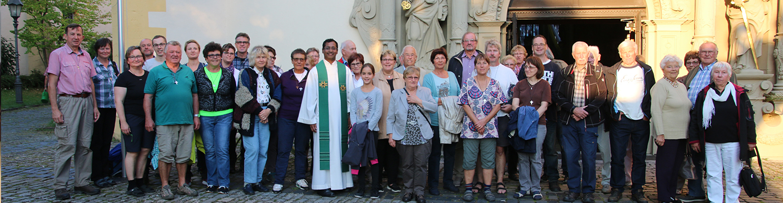 Auf dem Bild steht die Kirchengemeinde zusammen mit dem Pfarrer vor dem Eingang der Kirche
