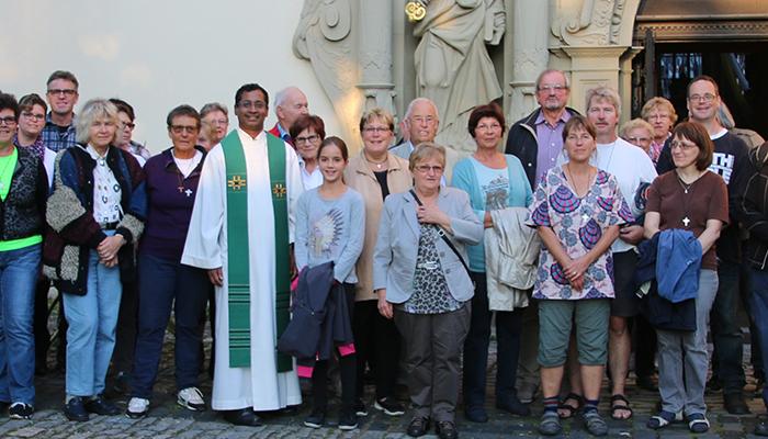 Auf dem Bild steht die Kirchengemeinde zusammen mit dem Pfarrer vor dem Eingang der Kirche